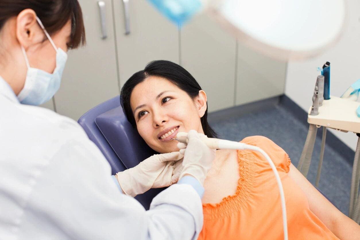 A woman getting her teeth checked by an dentist.